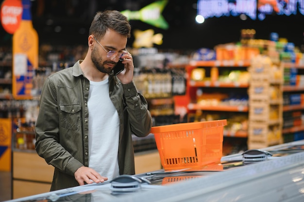 Un bel giovane che sceglie cibo al supermercato.