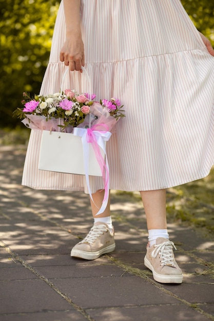 Un bel mazzo di fiori in una scatola nelle mani di una bella ragazza che cammina lungo la strada