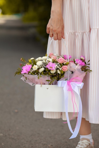 Un bel mazzo di fiori in una scatola nelle mani di una ragazza