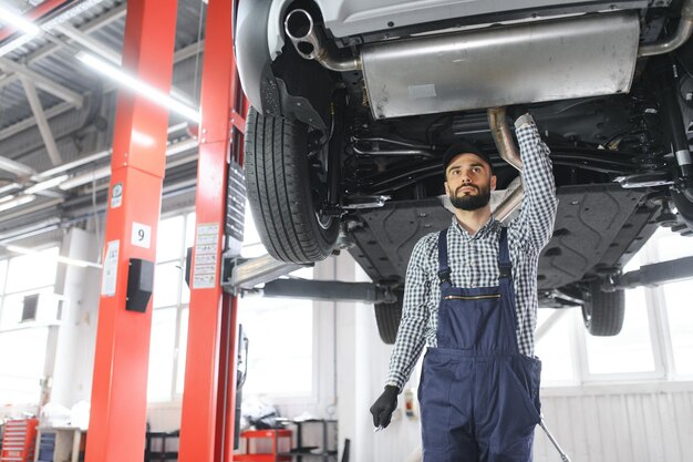 Un bel meccanico d'auto sta posando in un servizio di auto