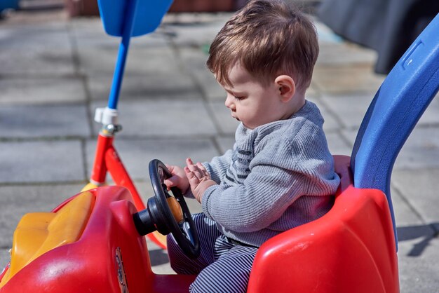 Un bel ragazzino sta giocando in una macchina rossa.