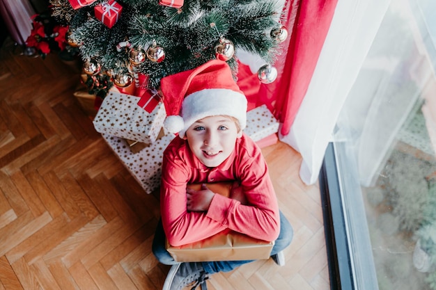 Un bel ragazzo a casa con i regali vicino all'albero di Natale
