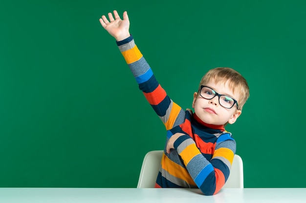 Un bel ragazzo con gli occhiali è seduto al tavolo alzò la mano Primo piano