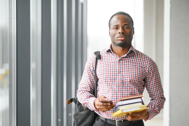 Un bel ragazzo del college che tiene dei libri nel campus.