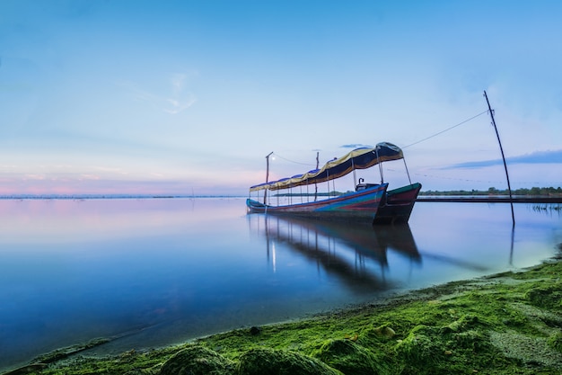 Un bel tramonto con la barca del pescatore e legato al palo per riparare. Vista del paesaggio.