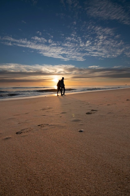 Un bel tramonto sulla spiaggia di Mazagon Spagna profilato da escursionisti sulla riva