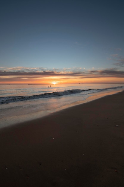 Un bel tramonto sulla spiaggia di Mazagon Spagna Sullo sfondo le sagome di due surfisti