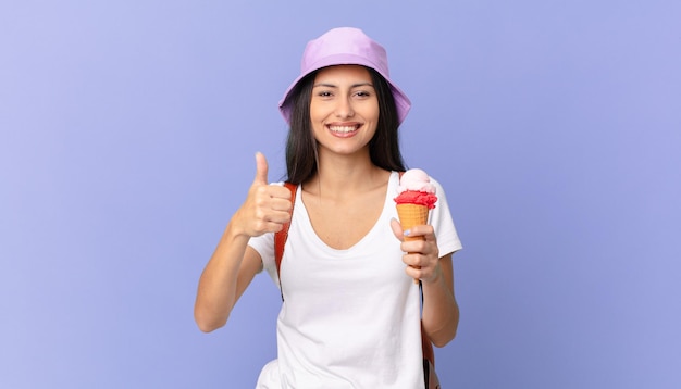 Un bel turista ispanico si sente orgoglioso, sorride positivamente con il pollice in alto e tiene in mano un gelato