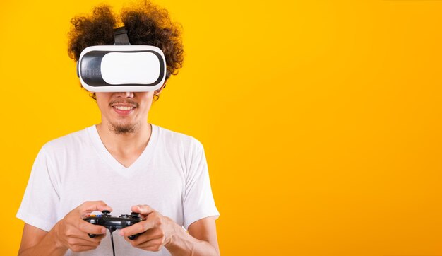 Un bell'uomo asiatico con i capelli ricci gioca con le cuffie per realtà virtuale o il vetro VR