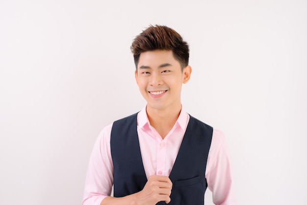 Un bell'uomo asiatico in piedi e sorride in posa su sfondo grigio