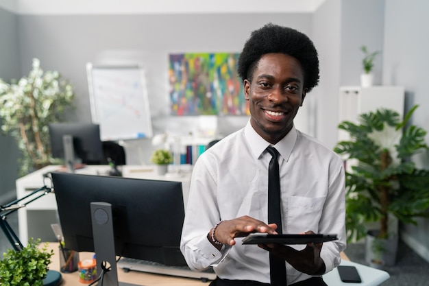 Un bell'uomo d'affari afroamericano del manager dell'azienda con un afro si siede alla scrivania vestito con un abito