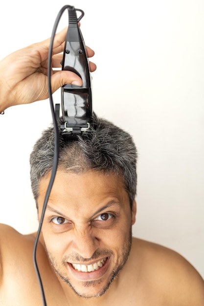 Un bell'uomo dai capelli grigi si sta tagliando i capelli da solo