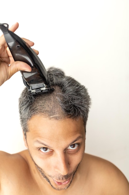 Un bell'uomo dai capelli grigi si sta tagliando i capelli da solo