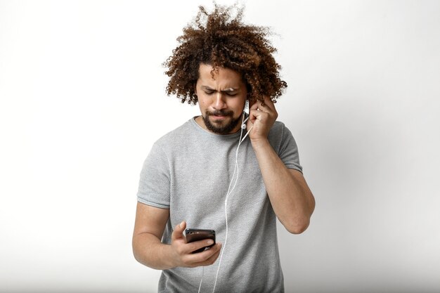 un bell'uomo dai capelli ricci sta ascoltando la musica negli auricolari