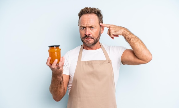 Un bell'uomo di mezza età che si sente confuso e perplesso, mostrando che sei pazzo. concetto di marmellata di pesche