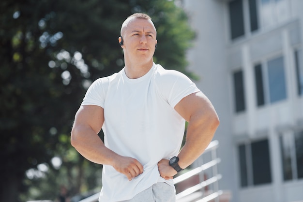 Un bell'uomo fitness in un abbigliamento sportivo, facendo stretching mentre si prepara per un serio esercizio fisico nella città moderna