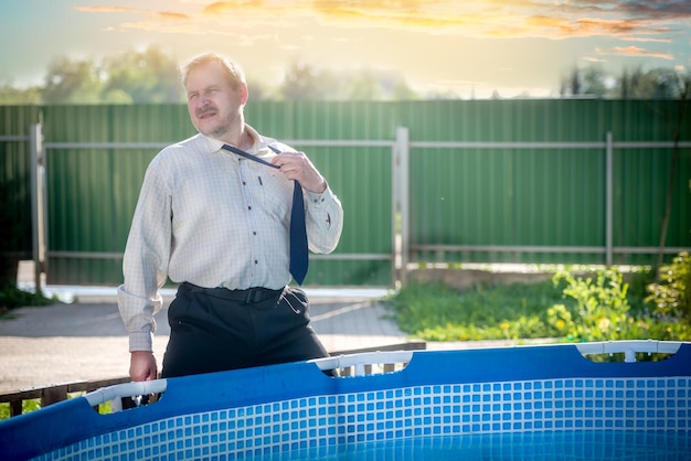 Un bell'uomo in giacca e cravatta soffre il caldo a bordo piscina