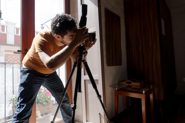 Un bell'uomo ispanico barbuto che fotografa la casa con una macchina fotografica professionale