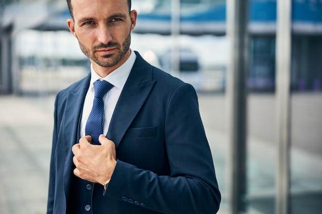 Un bell'uomo serio che si aggiusta la cravatta guardando di lato in modo deciso