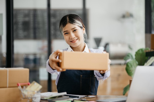 Un bellissimo imprenditore asiatico apre un negozio online che sta controllando gli ordini dei clienti che inviano merci attraverso un concetto di società di corriere di una donna che apre un'attività online