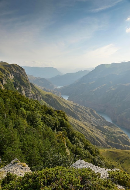 Un bellissimo paesaggio di montagne con rocce di cespugli e un fiume blu in un giorno d'estate Sulak Canyon