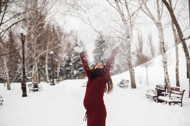 Un bellissimo ritratto di donna incinta all'aperto nel parco innevato