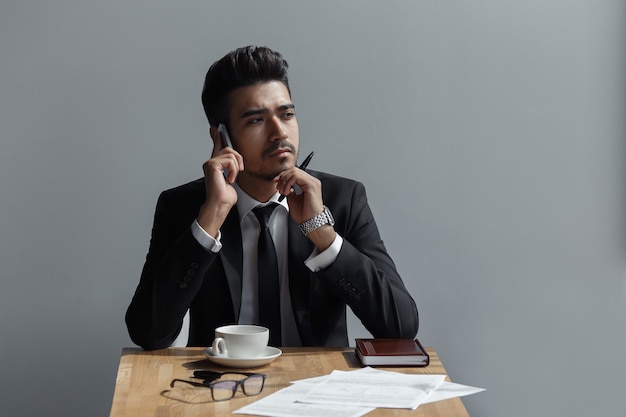 Un bellissimo uomo di successo che parla al telefono in ufficio al bar