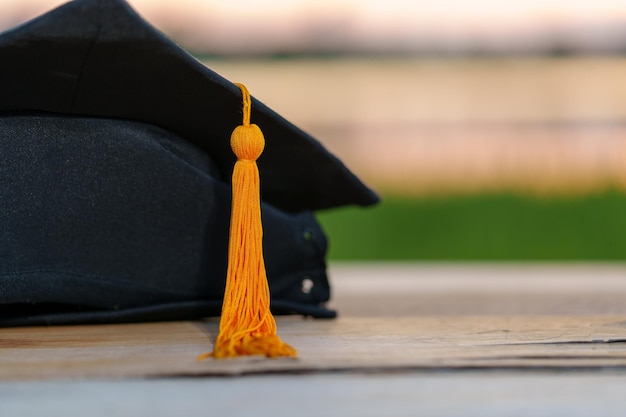 Un berretto graduato nero e un certificato posto su una scrivania in legno