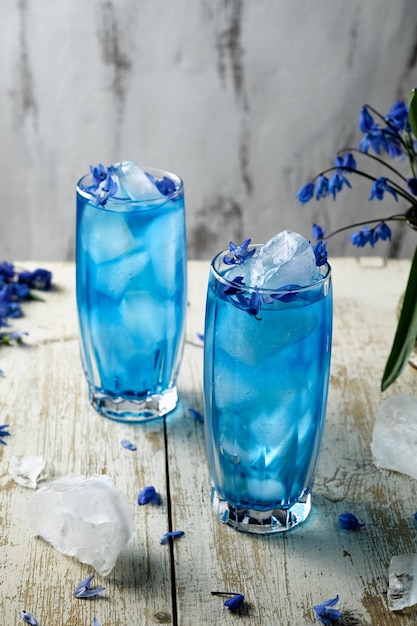 un bicchiere alto con blu beve una bevanda blu con ghiaccio in un bicchiere trasparente