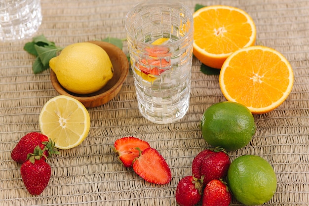 Un bicchiere alto di acqua con ghiaccio a fette arance, limoni, lime e fragola