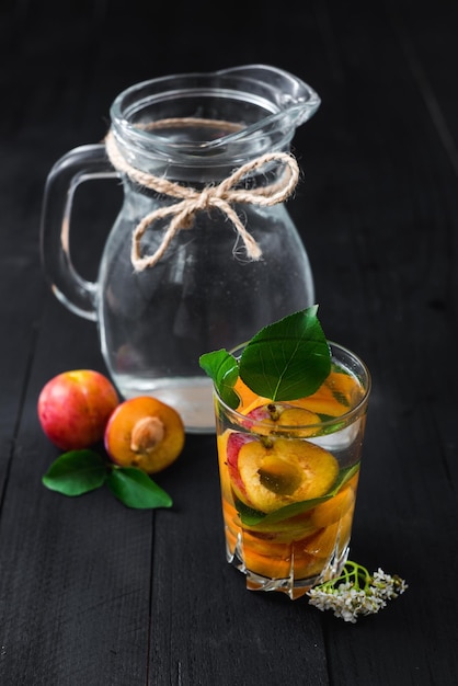 Un bicchiere d'acqua con dentro pezzi di prugne e albicocche. Copia spazio. Cibo sano, disintossicazione