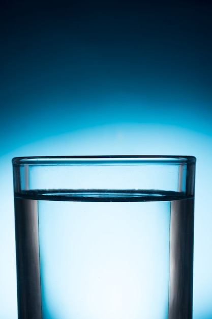Un bicchiere d&#39;acqua su sfondo blu.
