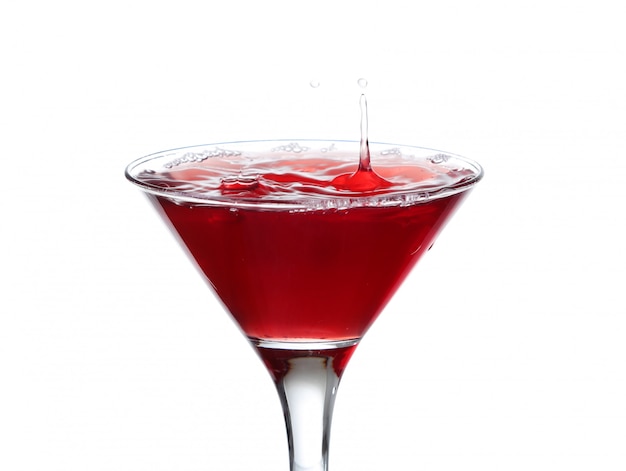 Un bicchiere da martini su uno sfondo bianco; l'acqua si increspa e schizza come un'oliva verde spagnola con pimento viene lasciata cadere nel bicchiere; formato orizzontale