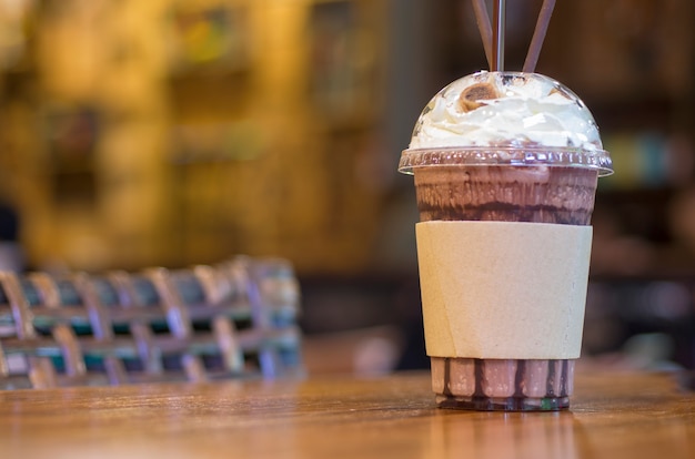 Un bicchiere di acqua di cioccolato è posto su un tavolo in legno con uno sfondo sfocato.