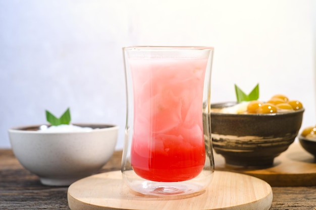 un bicchiere di acqua di cocco con sciroppo rosso su un tavolo di legno Pasto iftar Ramadan