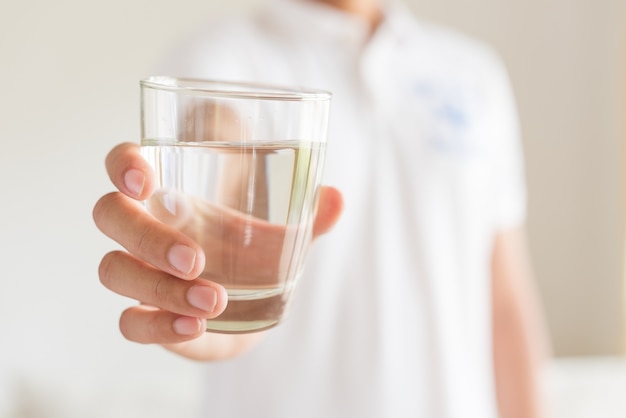 Un bicchiere di acqua minerale pulita nelle mani dell&#39;uomo. Concetto di bevanda salutare