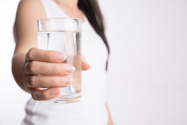 Un bicchiere di acqua minerale pulita nelle mani della donna. Concetto di bevanda salutare