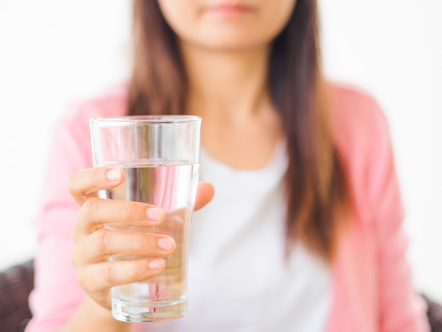 Un bicchiere di acqua minerale pulita nelle mani della donna.