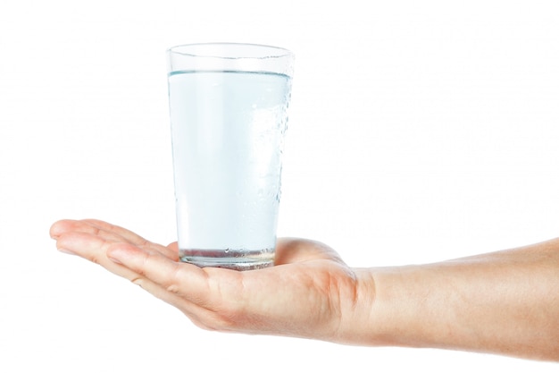 Un bicchiere di acqua pulita e fresca nella mano dell'uomo. Su un muro bianco