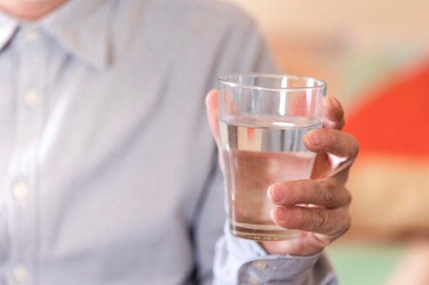 Un bicchiere di acqua pulita o acqua minerale nelle mani dell'uomo Concetto di bevanda sana per la protezione dell'ambiente