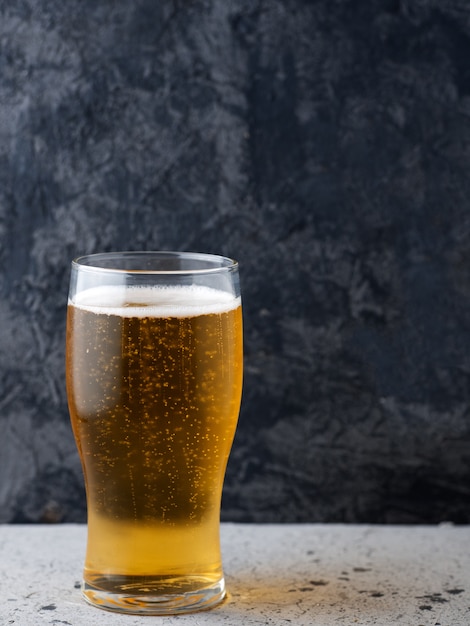 Un bicchiere di birra chiara su uno sfondo scuro