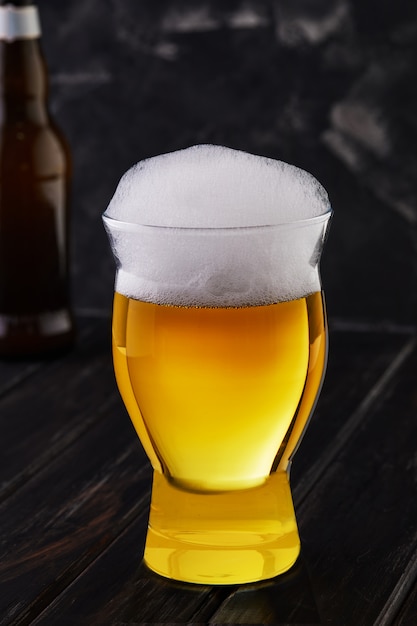 Un bicchiere di birra con abbondante schiuma nella parte superiore del bicchiere