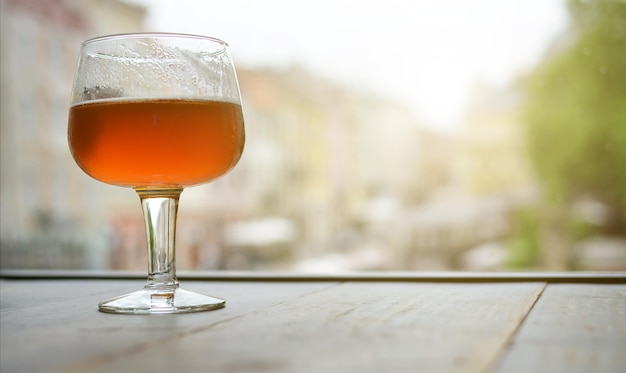Un bicchiere di birra su un tavolo di legno vicino alla finestra