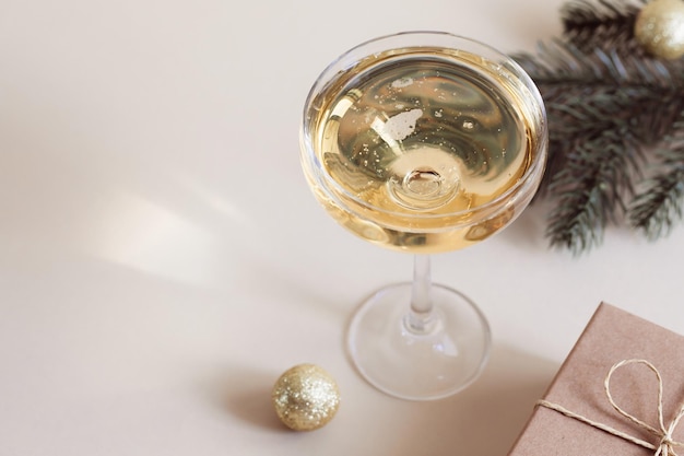 Un bicchiere di champagne una confezione regalo e un ramo di abete Natale Capodanno