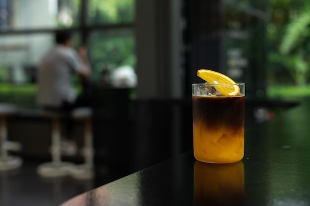 Un bicchiere di cocktail all'arancia si trova su un bancone del bar.