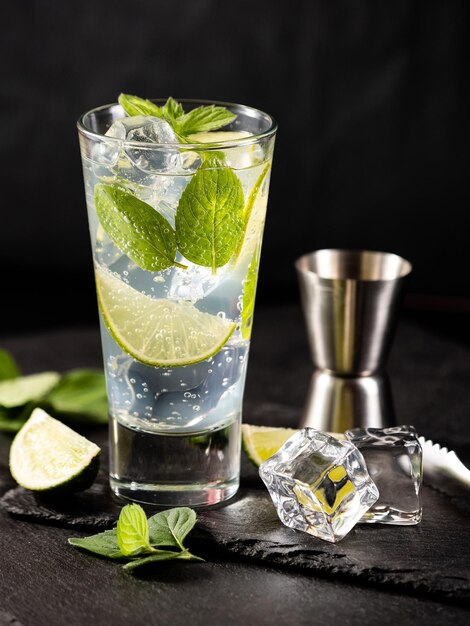 Un bicchiere di cocktail mojito con lime alla menta e cubetti di ghiaccio su sfondo nero