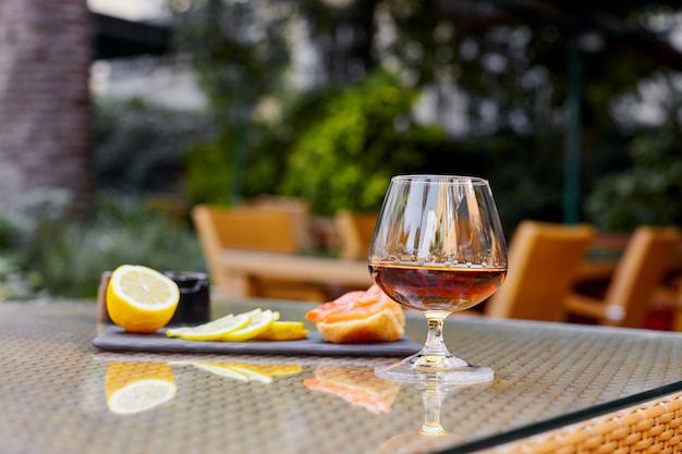 Un bicchiere di cognac, fette di limone, un panino giacciono sul tavolo sulla terrazza del ristorante