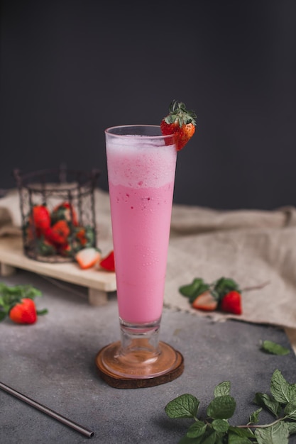 Un bicchiere di frappè alla fragola con fragole sul lato