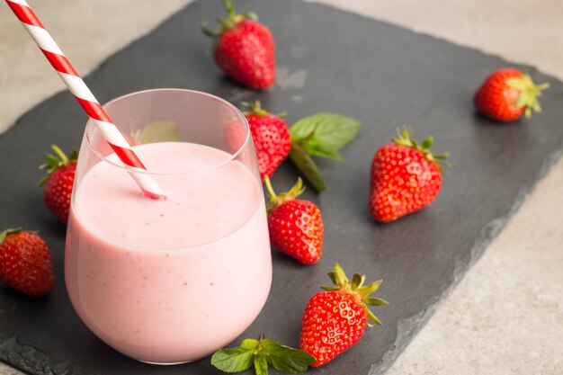 Un bicchiere di frullato di fragole fresche su sfondo rosa