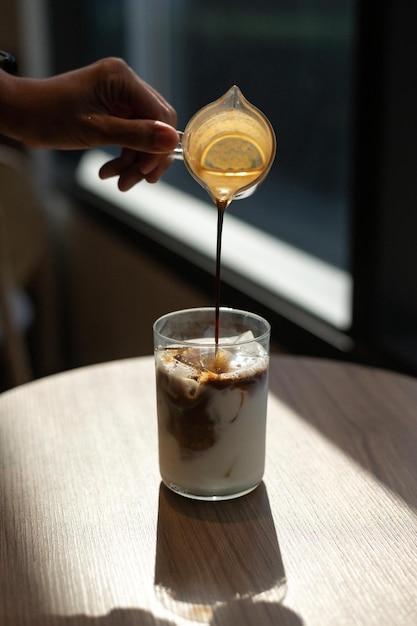 Un bicchiere di latte con un cucchiaino che ci versa dentro un cappuccino.